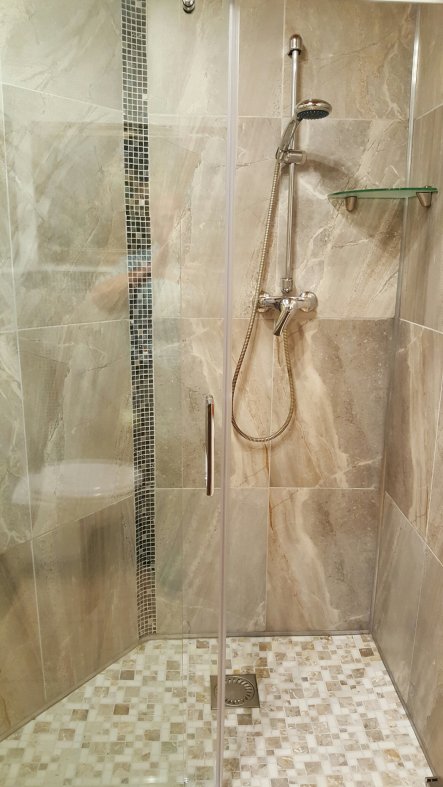 Duschtasse mit Marmor-Mosaik und große Wandfliesen grau, in Steinoptik